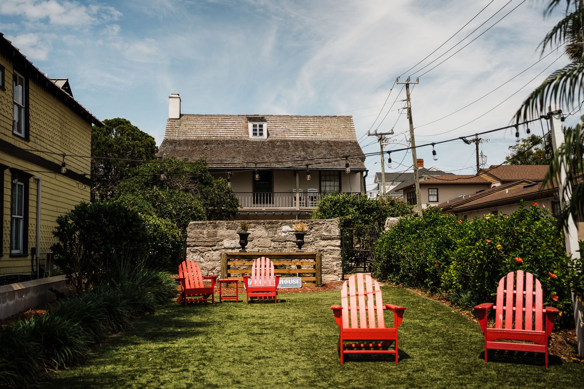 A tranquil Florida courtyard with red chairs and mature plantings, an example of a higher-end landscaping investment.