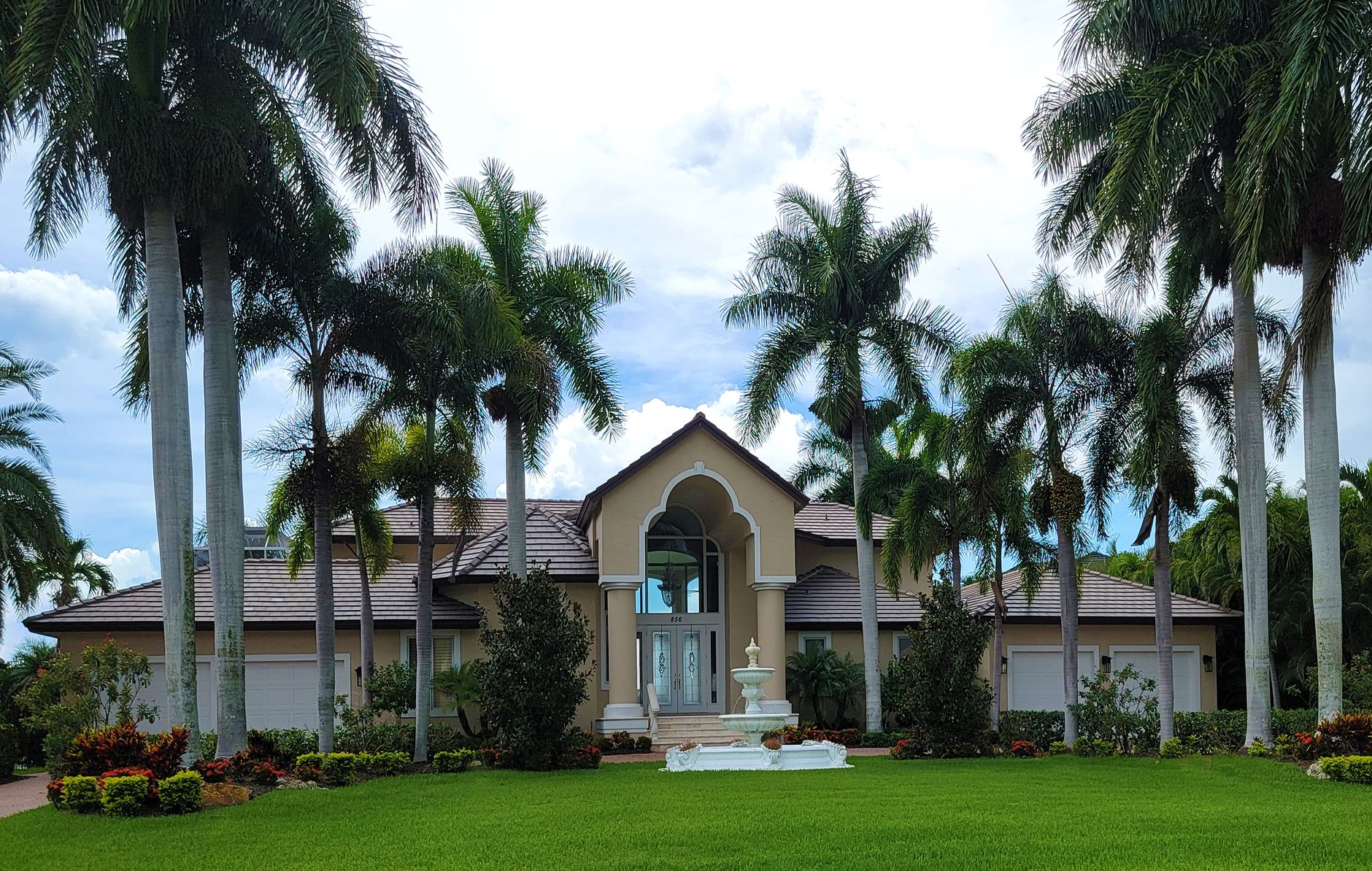 Stunning Florida home exterior surrounded by palm trees, the payoff of a full landscaping investment.