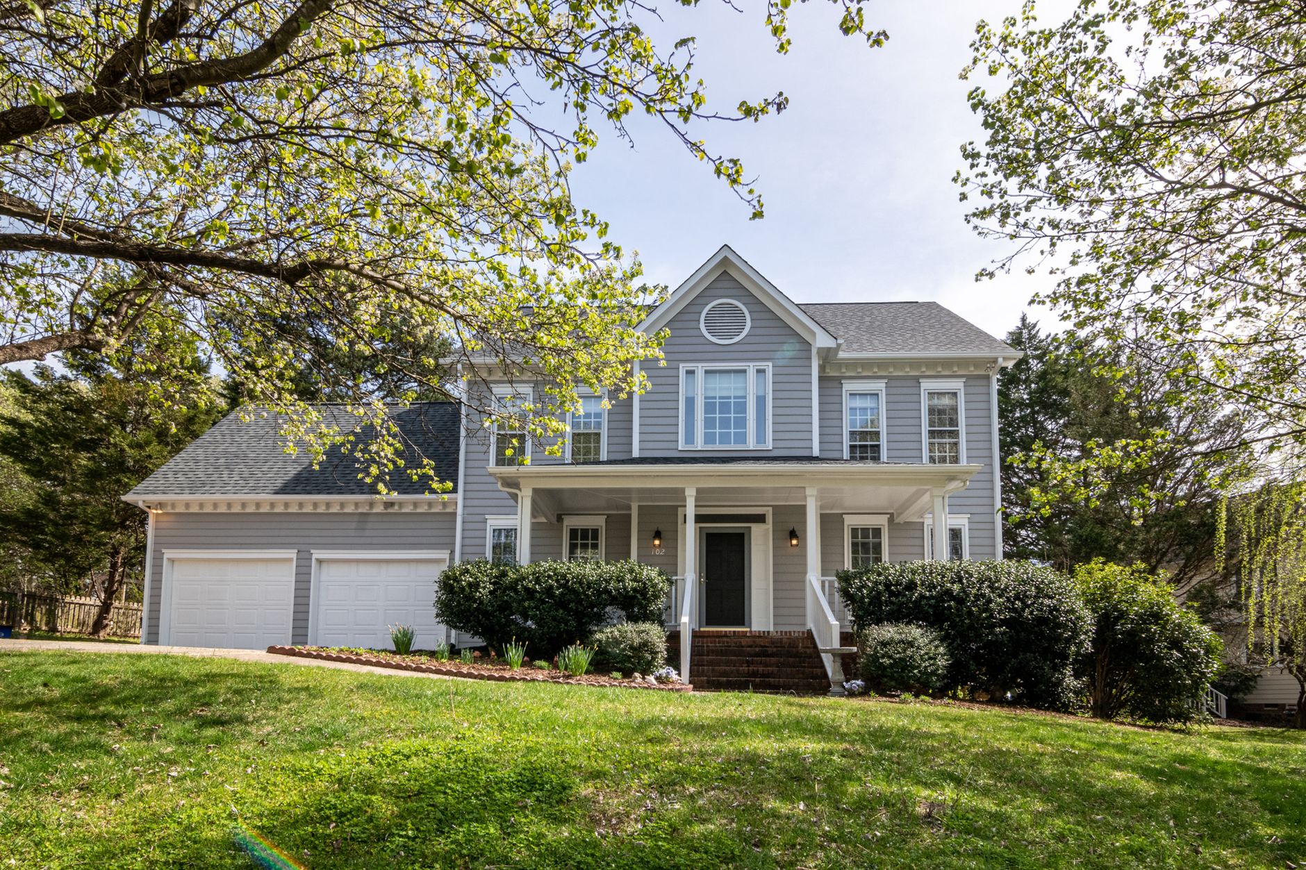 Suburban house surrounded by mature trees and lush greenery on a well landscaped lot